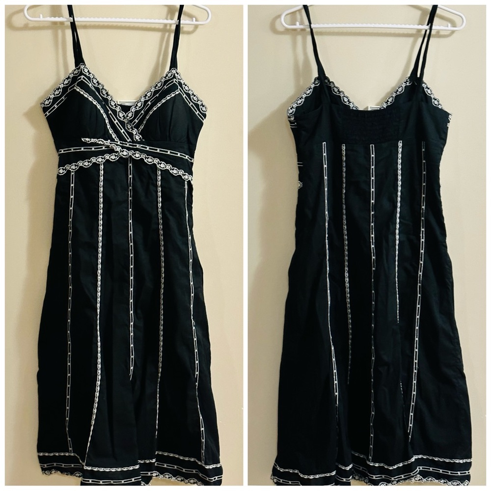 Knee length medium sized black dress with white embroidery.